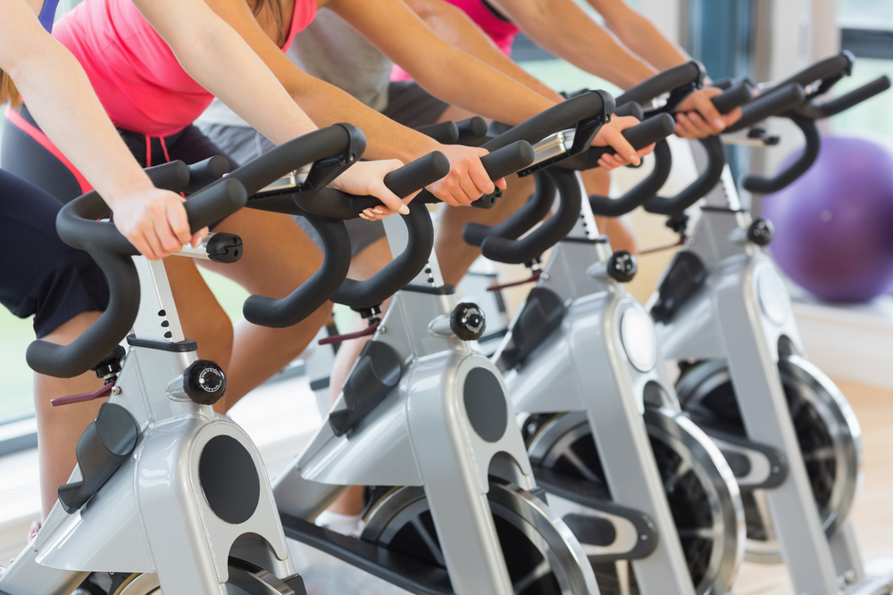 Mid section of four people working out at spinning class in gym